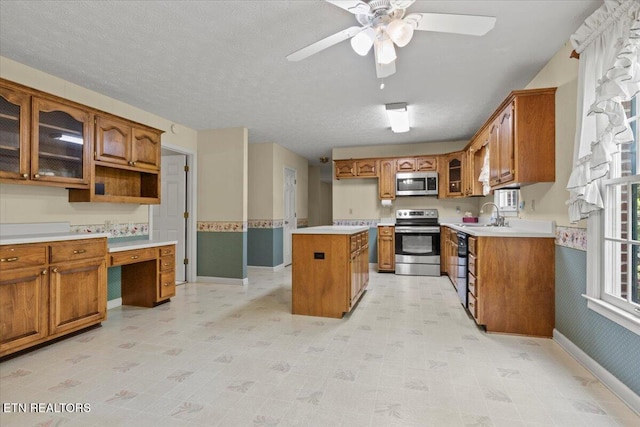 kitchen with stainless steel appliances, brown cabinetry, glass insert cabinets, and ceiling fan