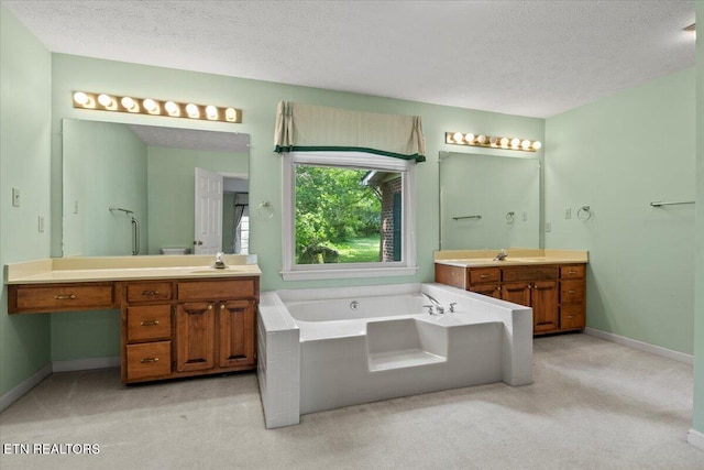 bathroom with a textured ceiling, a bath, two vanities, carpet flooring, and baseboards