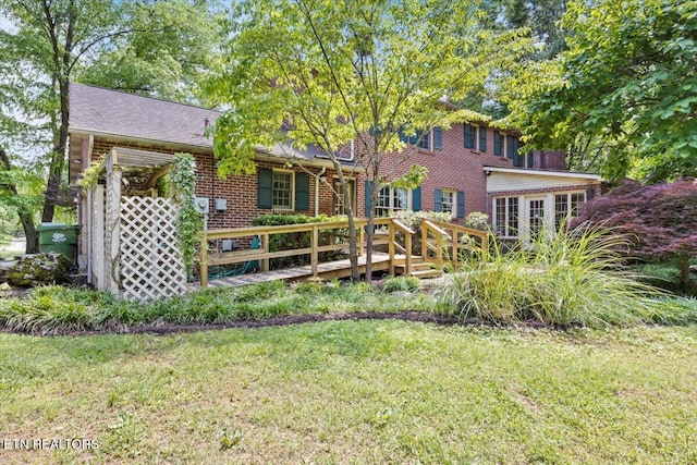 back of house with a yard, a deck, and brick siding