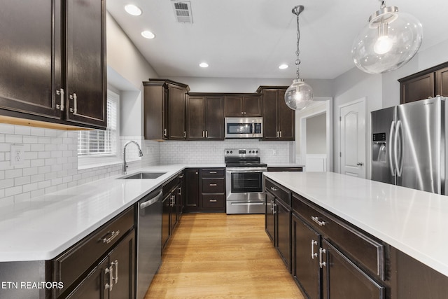 12888 Lily Pond Ln, Knoxville, TN 37922 - kitchen with appliances with stainless steel finishes, a sink, dark brown cabinets, light countertops, and hanging light fixtures