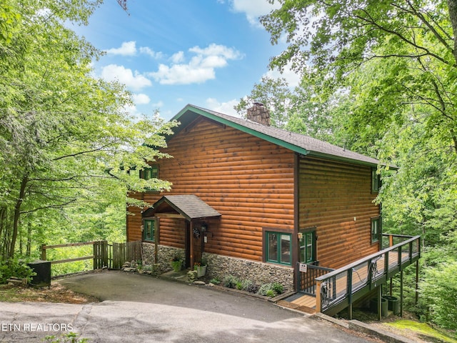 529 Deer Path Ln, Gatlinburg, TN 37738 - view of home's exterior with a chimney, stone siding, log veneer siding, and a shingled roof