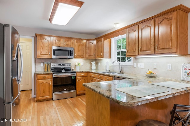 157 Garfield Ct, Crossville, TN 38558 - kitchen with stainless steel appliances, a sink, a peninsula, light wood-style floors, and a breakfast bar