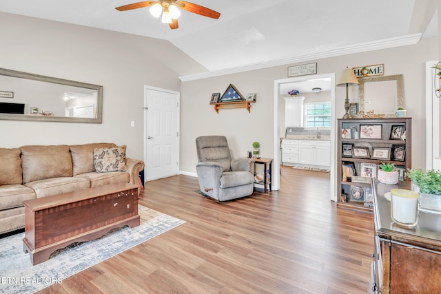 living room with ceiling fan, light wood-type flooring, vaulted ceiling, crown molding, and baseboards