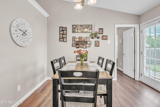 dining room with light wood-style flooring, baseboards, lofted ceiling, and a chandelier