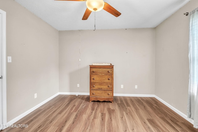 spare room with wood finished floors, a ceiling fan, and baseboards