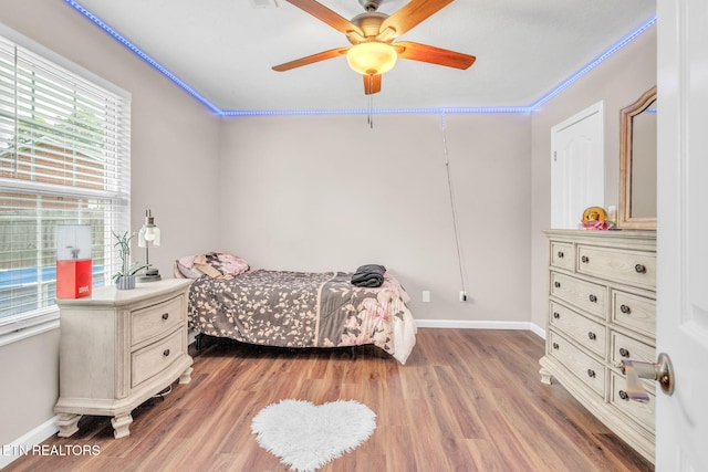 bedroom featuring light wood-style flooring, baseboards, ornamental molding, and a ceiling fan