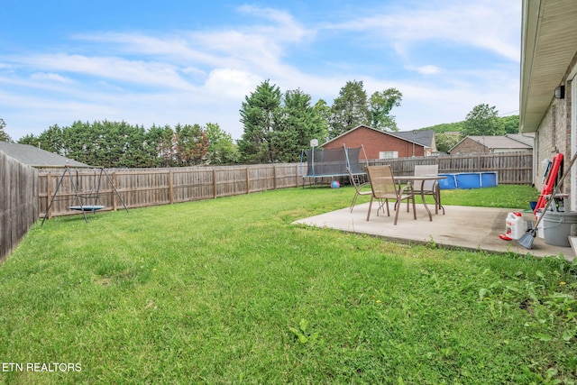 view of yard with a trampoline and a patio area