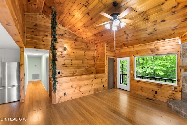 unfurnished living room featuring vaulted ceiling, wood-type flooring, wood walls, ceiling fan, and wood ceiling