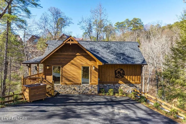 chalet / cabin featuring roof with shingles and stone siding