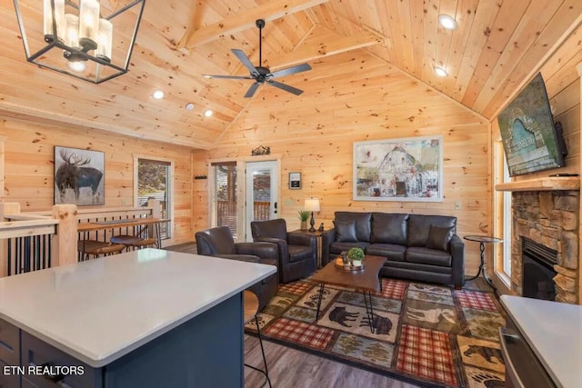 living area featuring wood ceiling, vaulted ceiling, wooden walls, wood finished floors, and a ceiling fan