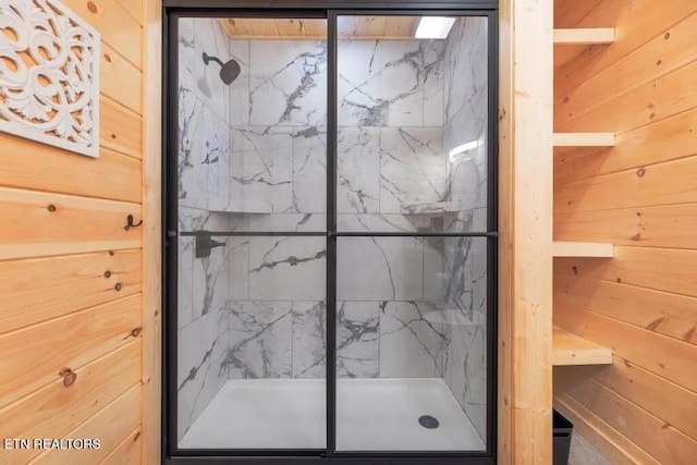 full bath with a marble finish shower and wooden walls