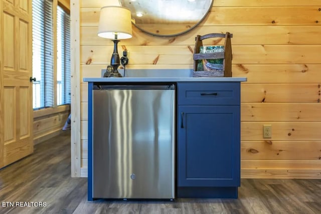 bar area featuring fridge, dark wood finished floors, and wooden walls