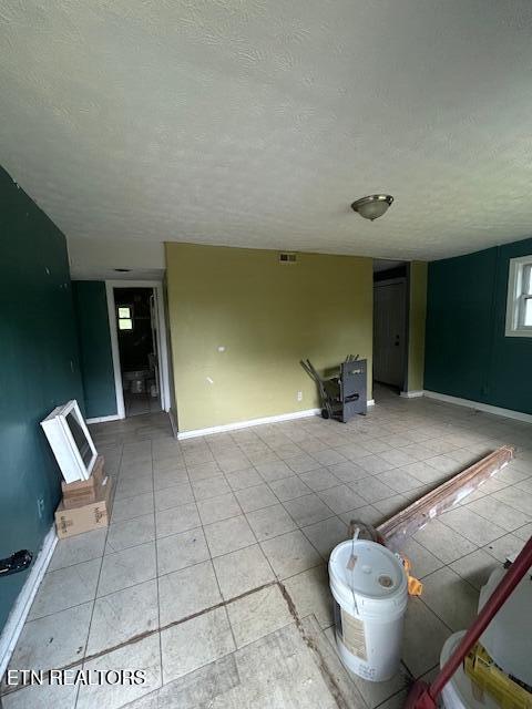 3614 Selma Ave, Knoxville, TN 37914 - unfurnished living room with a textured ceiling, baseboards, and light tile patterned flooring