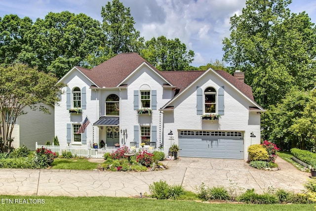view of front of house featuring a garage, a chimney, concrete driveway, and fence