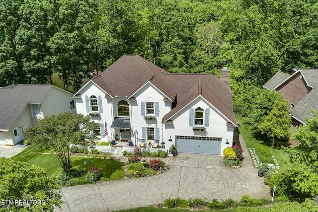 view of front facade featuring asphalt driveway, a garage, a chimney, a porch, and a shingled roof