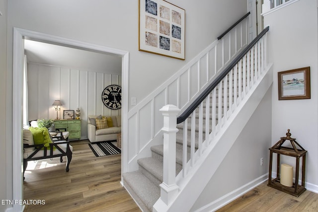 stairs with wood finished floors and a decorative wall