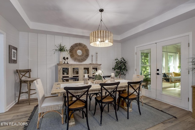 dining room with french doors, wood finished floors, a raised ceiling, and a chandelier