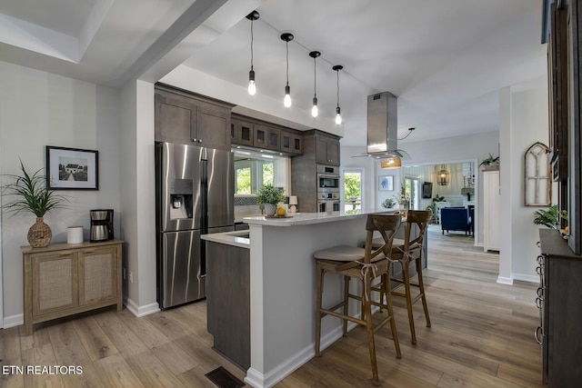 kitchen featuring appliances with stainless steel finishes, dark brown cabinetry, island exhaust hood, light countertops, and light wood finished floors