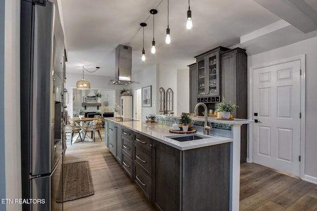 kitchen featuring stainless steel refrigerator with ice dispenser, a sink, extractor fan, open floor plan, and a spacious island