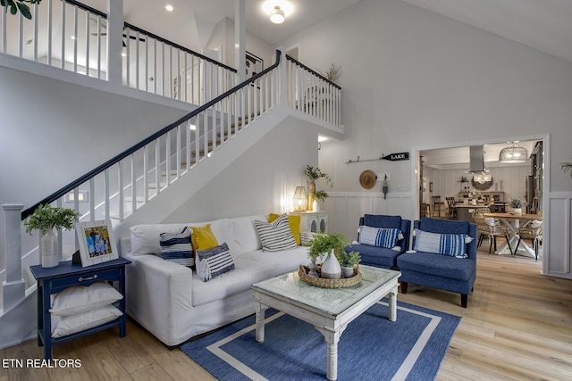 living area with a towering ceiling, wood finished floors, and stairway