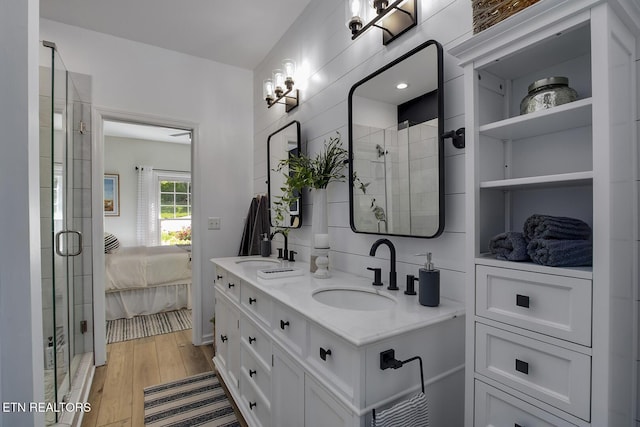 full bathroom with connected bathroom, a shower stall, wood finished floors, and double vanity