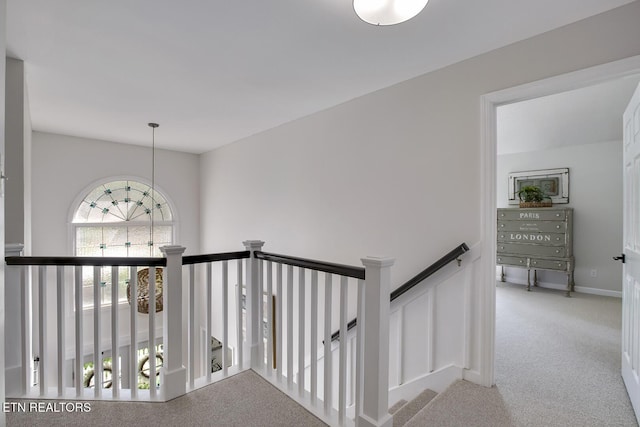 hallway with carpet flooring and an upstairs landing