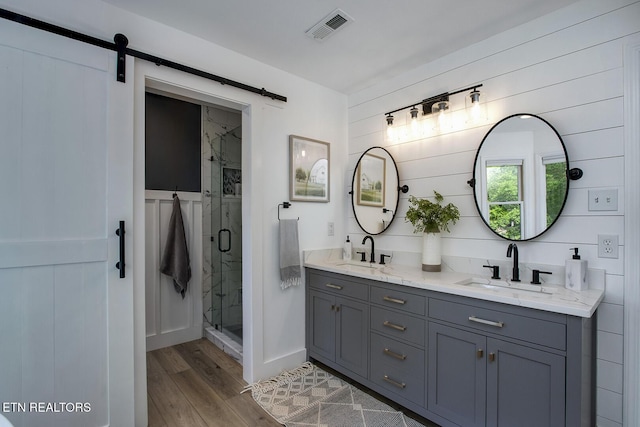 full bath with wood finished floors, a shower stall, and double vanity