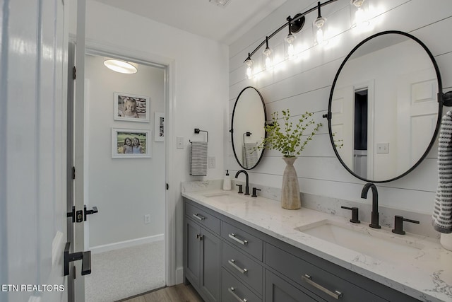 full bath with double vanity, wood finished floors, and baseboards