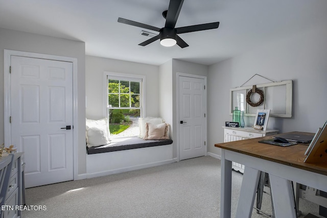office featuring a ceiling fan, light carpet, and baseboards