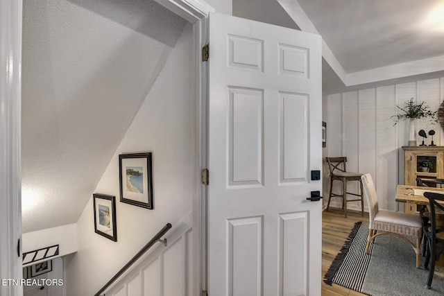 stairs with wood finished floors and vaulted ceiling