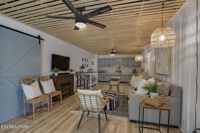 living area with ceiling fan, crown molding, light wood-style floors, wooden ceiling, and a barn door