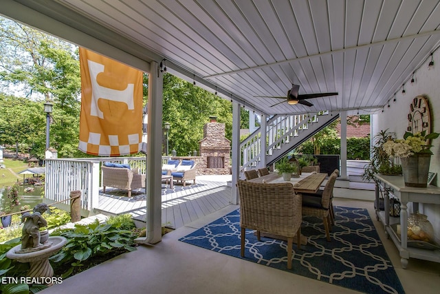 view of patio / terrace featuring stairway, ceiling fan, outdoor dining area, an outdoor living space with a fireplace, and a wooden deck