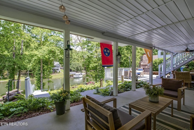 view of patio / terrace featuring a water view, stairway, an outdoor hangout area, and view of wooded area