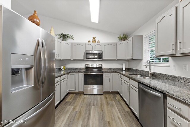 134 Jordan Dr, Caryville, TN 37714 - kitchen with stainless steel appliances, a sink, vaulted ceiling, light wood-type flooring, and dark stone counters