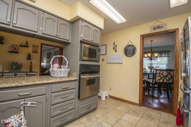 7745 Keswick Rd, Powell, TN 37849 - kitchen with stainless steel appliances, gray cabinets, a chandelier, and light tile patterned floors