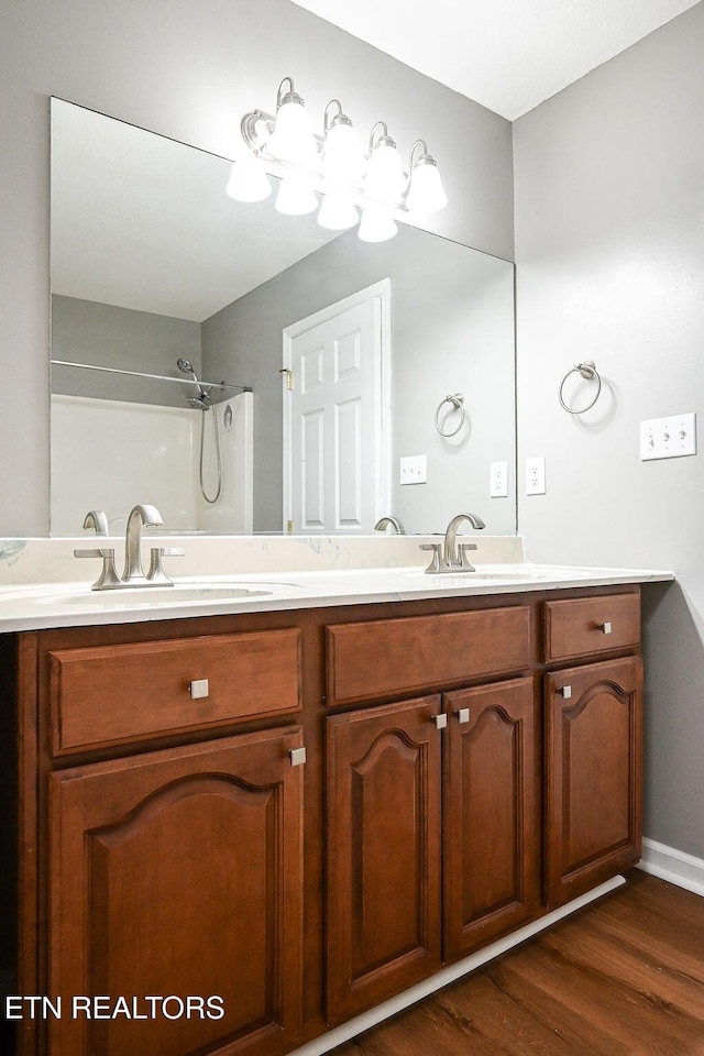 169 Claire St, Benton, TN 37307 - bathroom featuring double vanity, wood finished floors, baseboards, and a shower