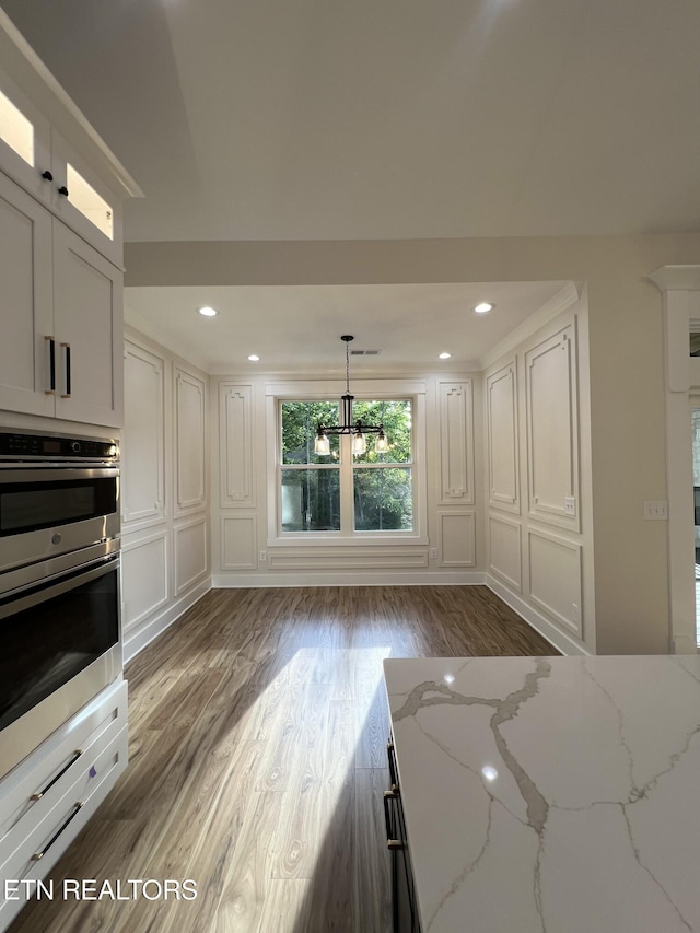 kitchen featuring light wood-type flooring, a chandelier, double oven, light stone counters, and recessed lighting