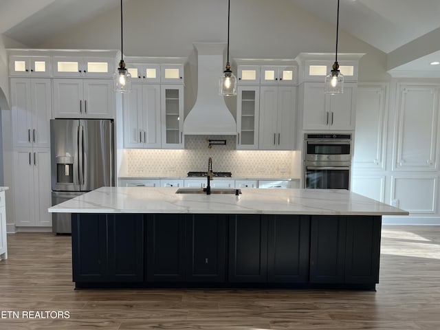kitchen featuring vaulted ceiling, appliances with stainless steel finishes, premium range hood, decorative backsplash, and a large island