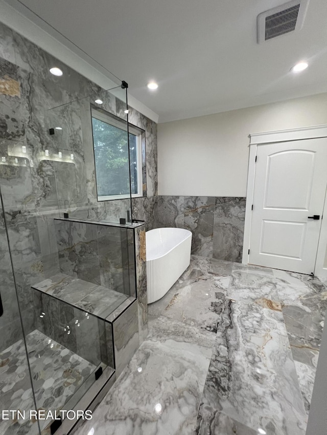 bathroom featuring a freestanding bath, a marble finish shower, tile walls, marble finish floors, and recessed lighting