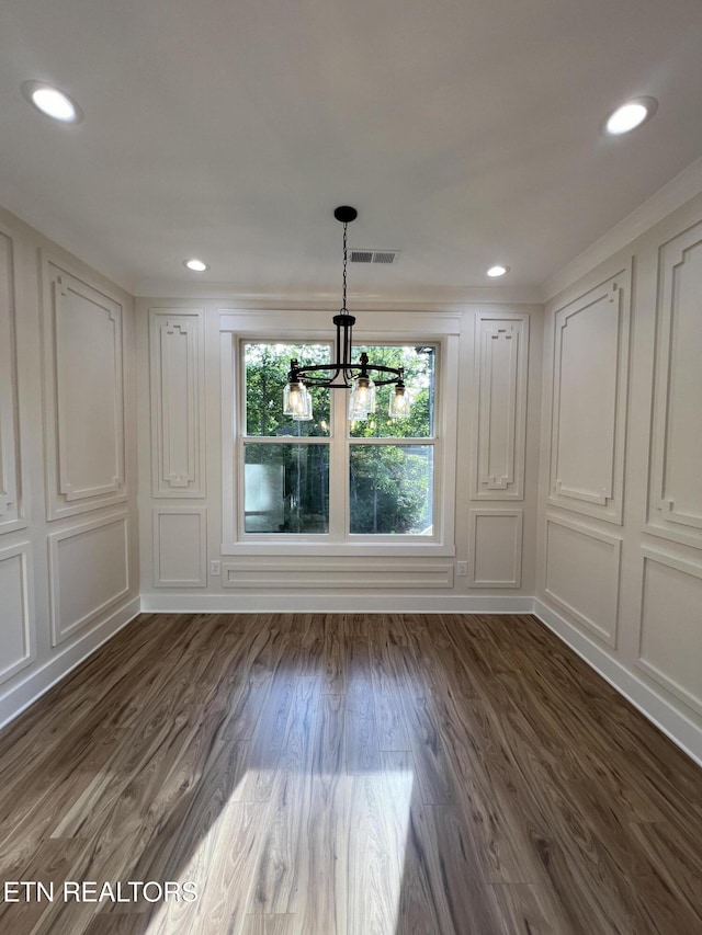 unfurnished dining area featuring a chandelier, a decorative wall, dark wood-style flooring, and recessed lighting