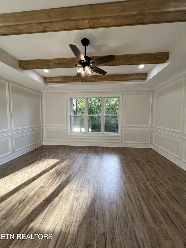 unfurnished room featuring a decorative wall, beamed ceiling, dark wood-style flooring, and a ceiling fan