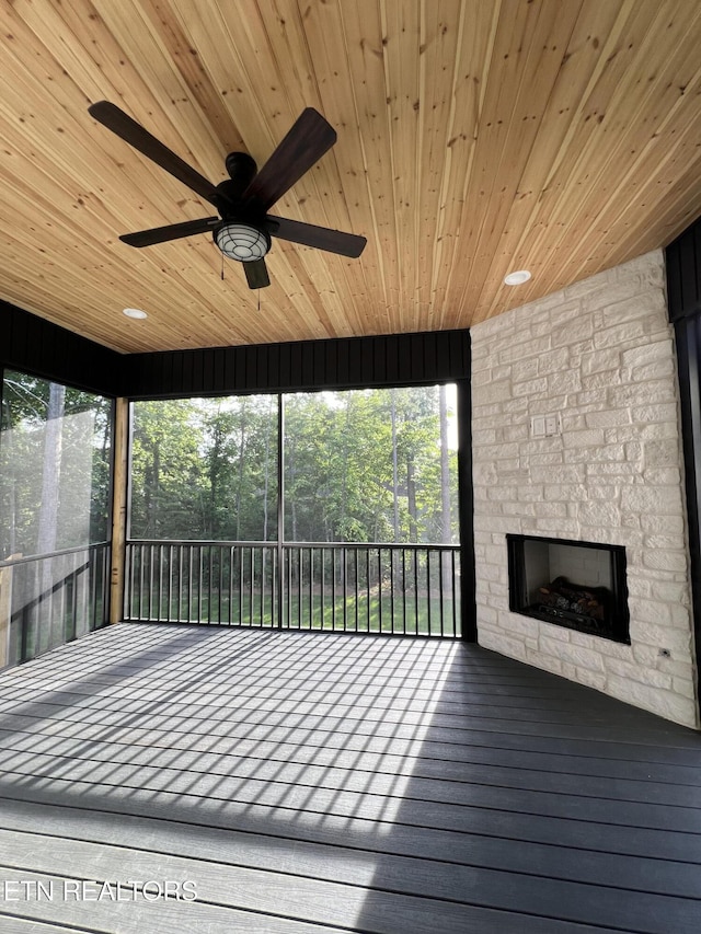 deck featuring an outdoor stone fireplace and a ceiling fan