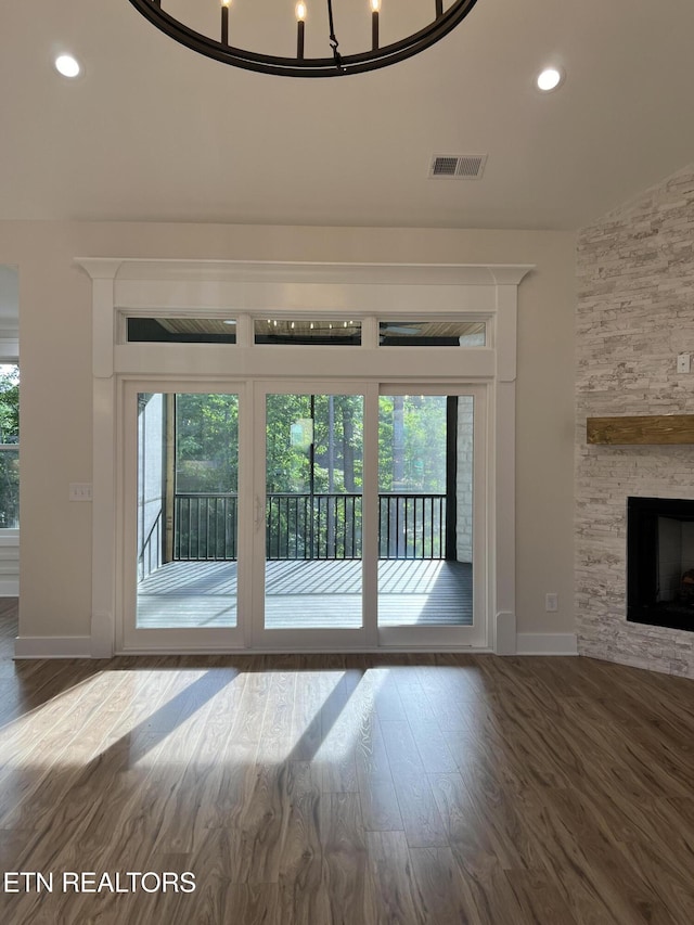entryway with healthy amount of natural light, wood finished floors, baseboards, recessed lighting, and a stone fireplace