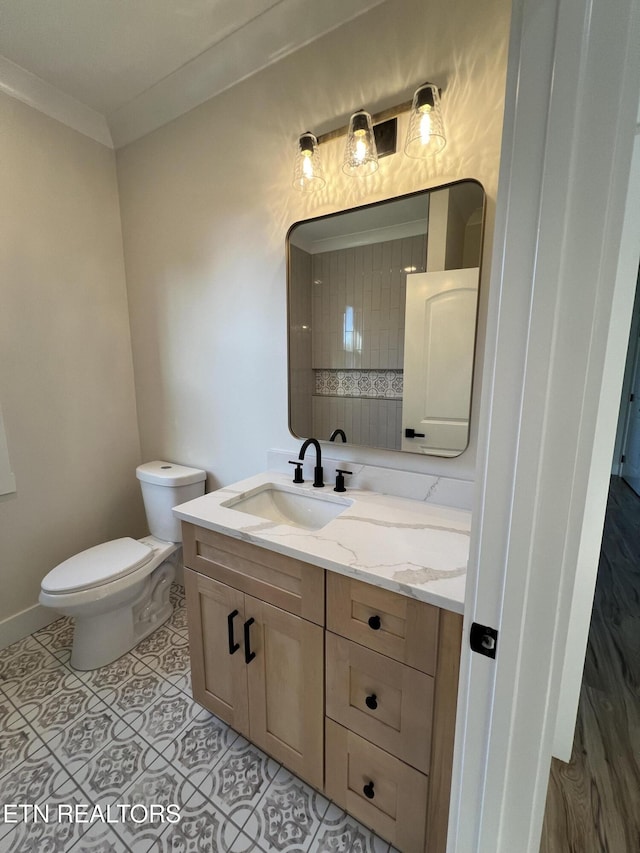 bathroom with vanity, toilet, crown molding, tile patterned flooring, and baseboards