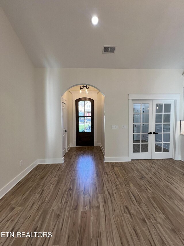foyer featuring arched walkways, wood finished floors, baseboards, french doors, and recessed lighting
