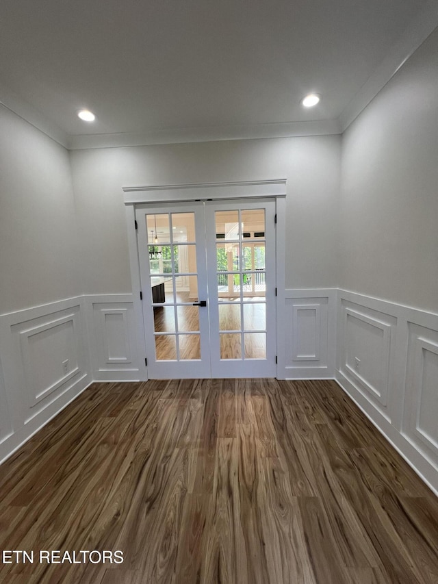 entryway with french doors, a decorative wall, wainscoting, dark wood finished floors, and ornamental molding