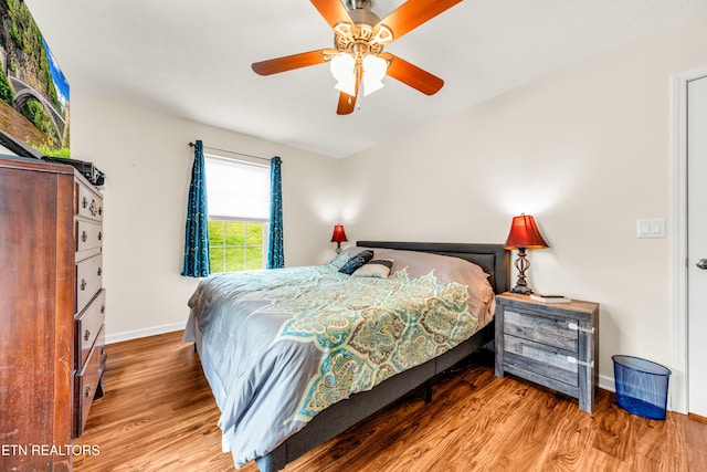 bedroom featuring wood finished floors, baseboards, and a ceiling fan