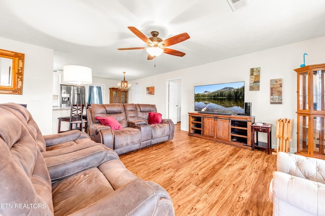 living room featuring ceiling fan, light wood-type flooring, and a chandelier