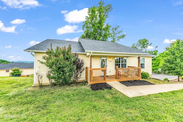 view of front of property with a deck, a front lawn, and roof with shingles