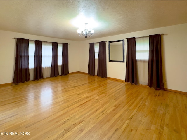 161 Cedar Ln, Rocky Top, TN 37769 - empty room with a chandelier, healthy amount of natural light, light wood-style floors, baseboards, and a textured ceiling